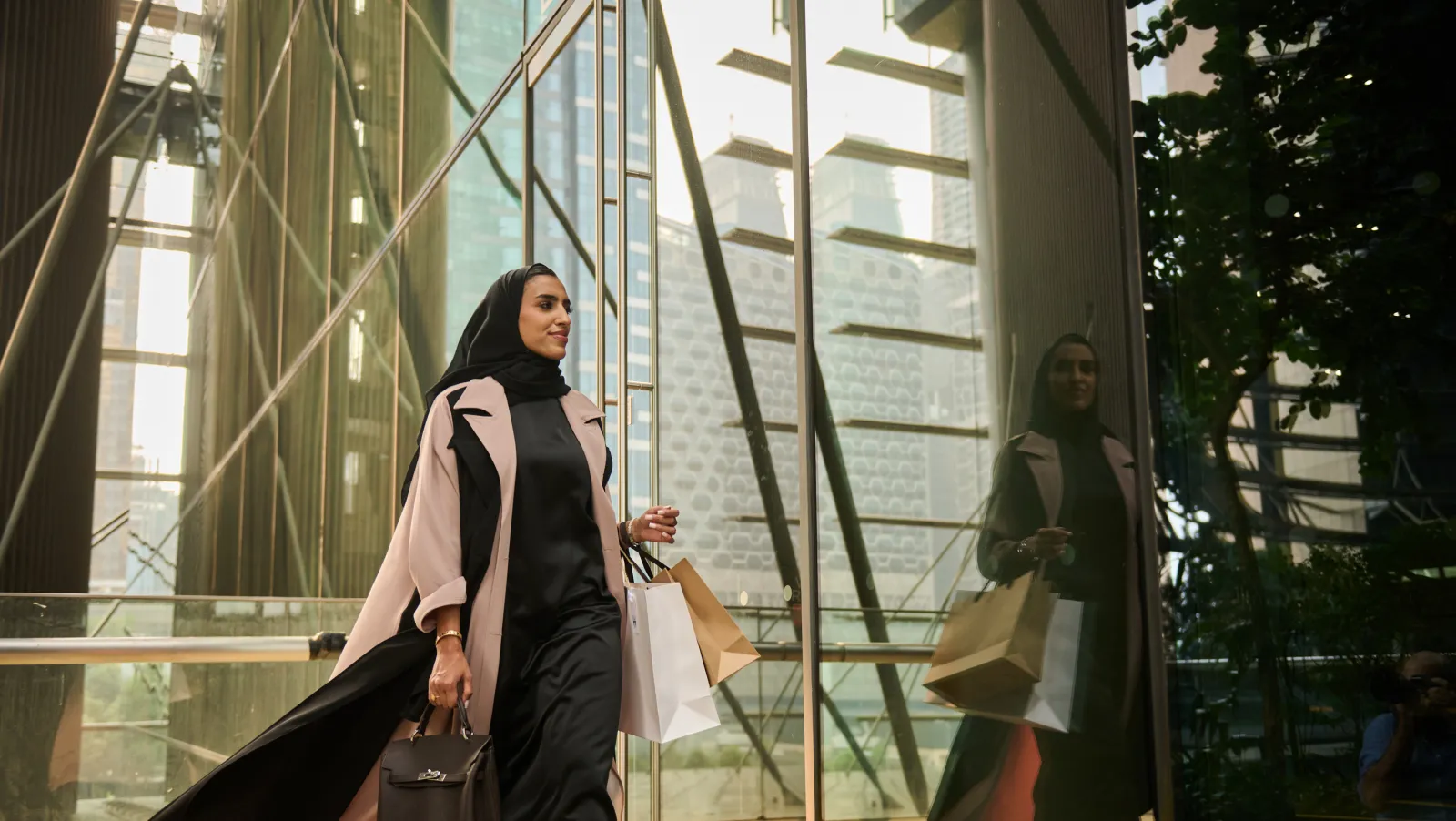 A shopper with bags walking along a glazed retail boulevard